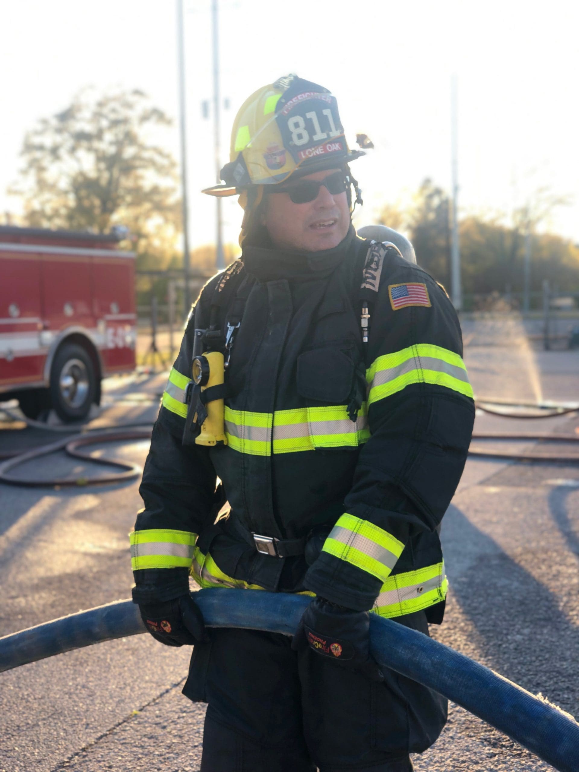John R Kowalski holds a fire hose in his firefighting gear.
