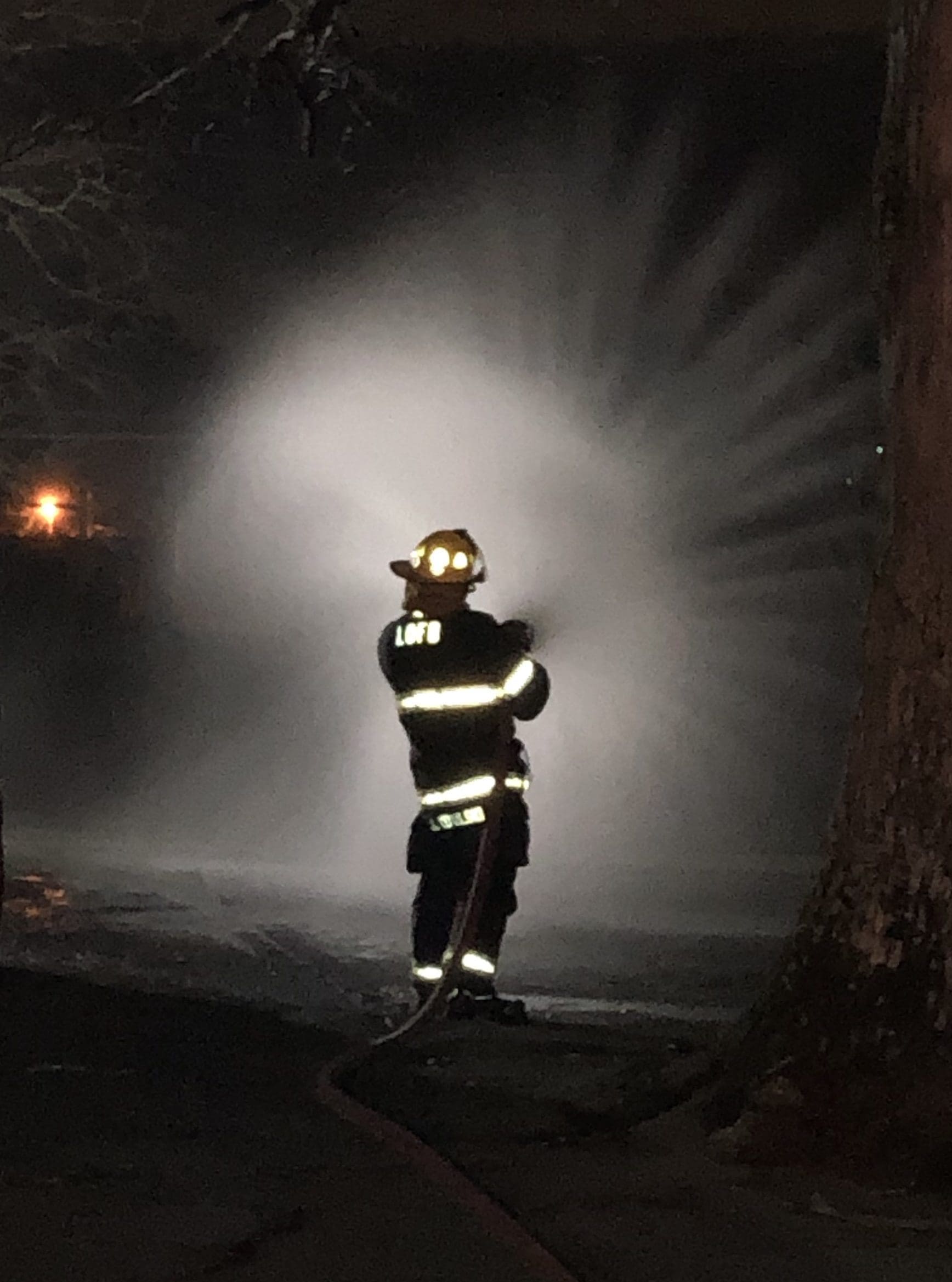 John R Kowalski uses a fire hose to extinguish a fire while working as a volunteer firefighter.