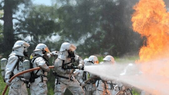 A group of firefighters work together to extinguish a fire.