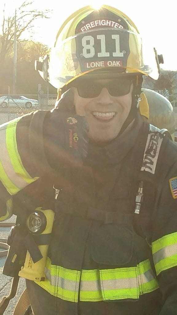 John R Kowalski smiles while wearing his volunteer firefighter gear.
